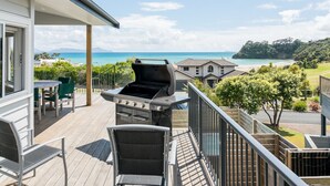 Un balcón con una parrilla, mobiliario exterior y vista a la playa y al océano.