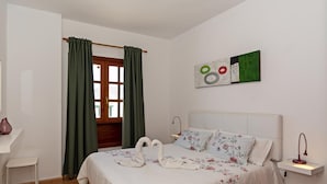 A bedroom with a bed, a desk, a chair, a window with curtains, and a wall with a painting. - Apartment Lima Center Playa Blanca By PVL (playa blanca)
