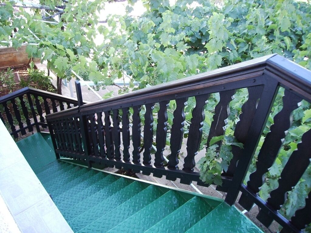Uma escadaria com corrimão preto e degraus antiderrapantes verdes.