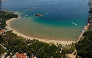 Enjoy a serene coastal retreat with a sandy beach, clear blue waters, and scenic views of the surrounding landscape.