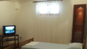 A small room with two single beds, a television on a side table, and a window with curtains. - Apartment in Kustici with Balcony, WIFI, Washing machine (4847-1) (Kustici)