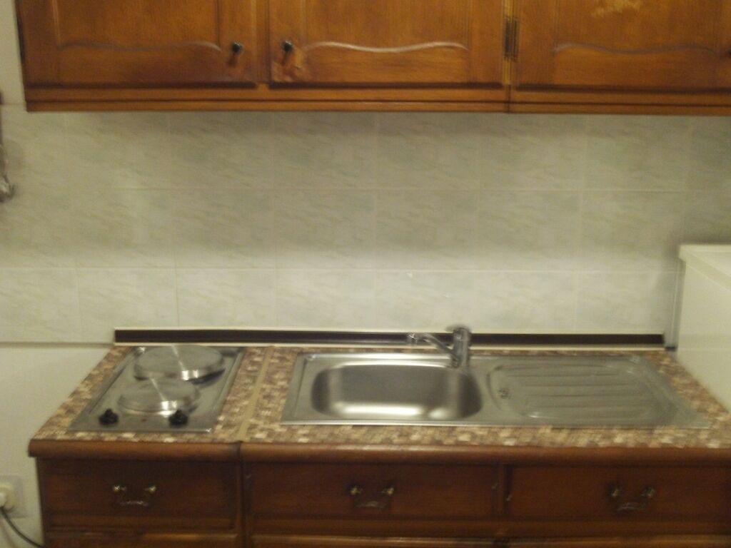 A kitchen with wooden cabinets, a granite countertop, a stainless steel sink, and a stove.