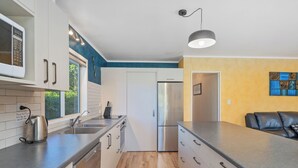 A modern kitchen with white cabinets, a stainless steel refrigerator, and a built-in oven.