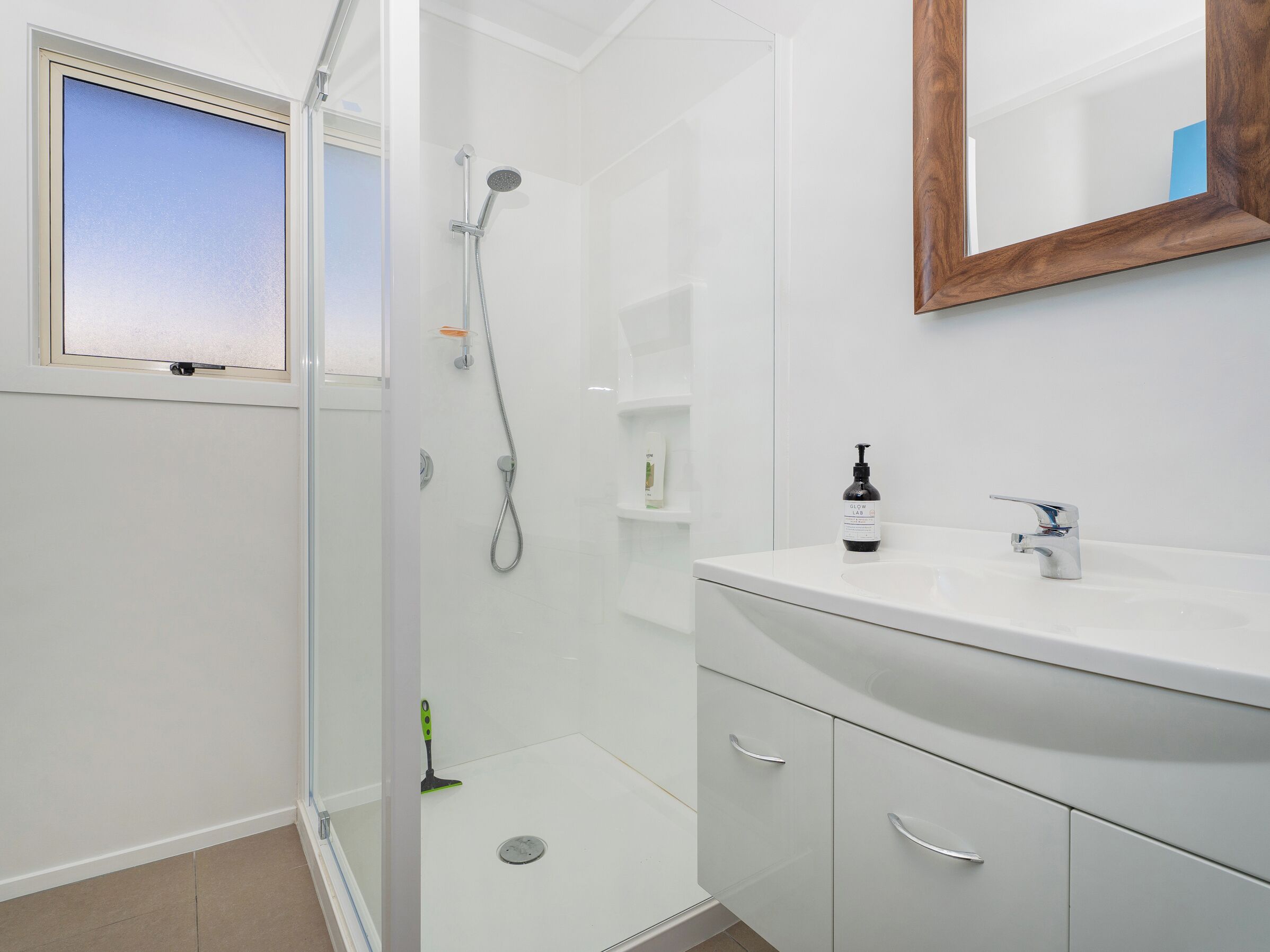 A modern bathroom with a glass shower enclosure, a white sink, and a mirror above the sink.