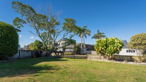 A residential backyard with a lawn, a large tree, and a wooden fence.