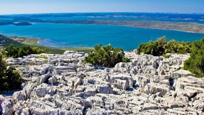 A rocky landscape with a view of a coastal city and a body of water. - Studio apartment in Pakoštane with Seaview, Terrace, Air condition, WIFI (4852-1) (Pakoštane)