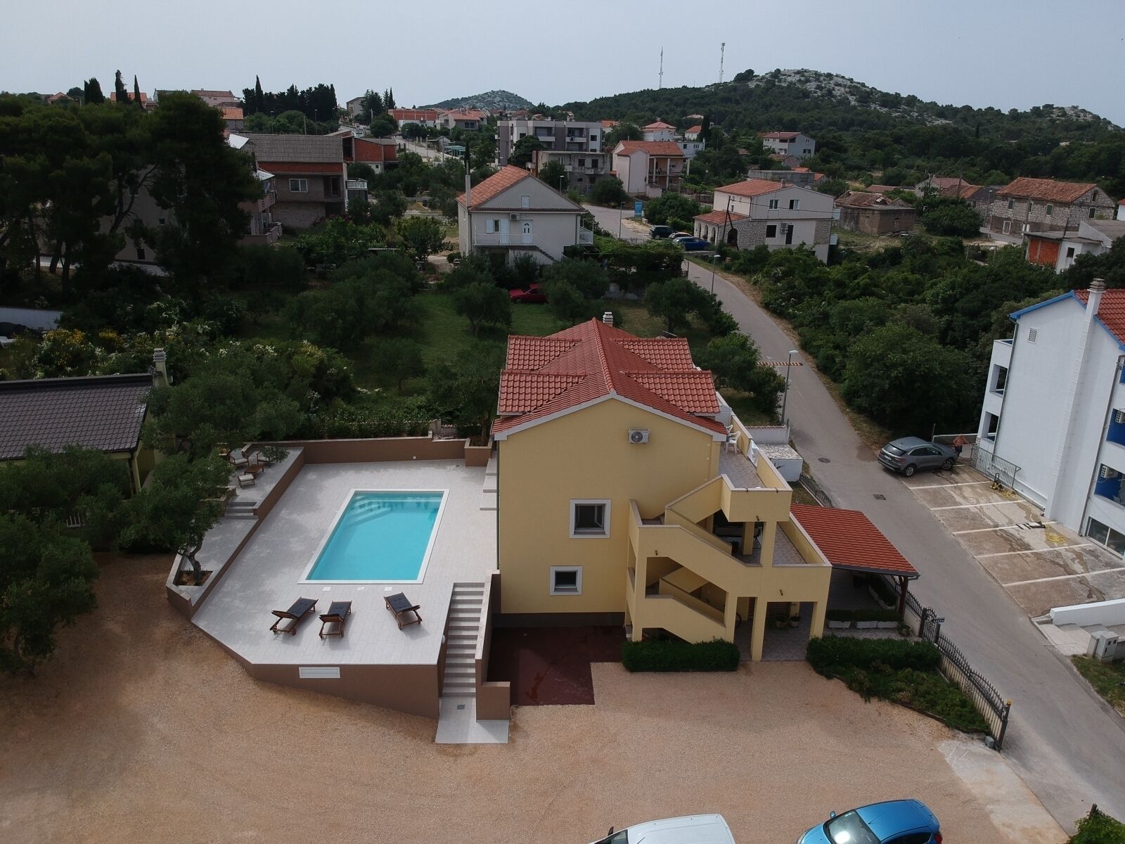A residential building with a swimming pool, a covered patio, and a staircase leading to a second floor.