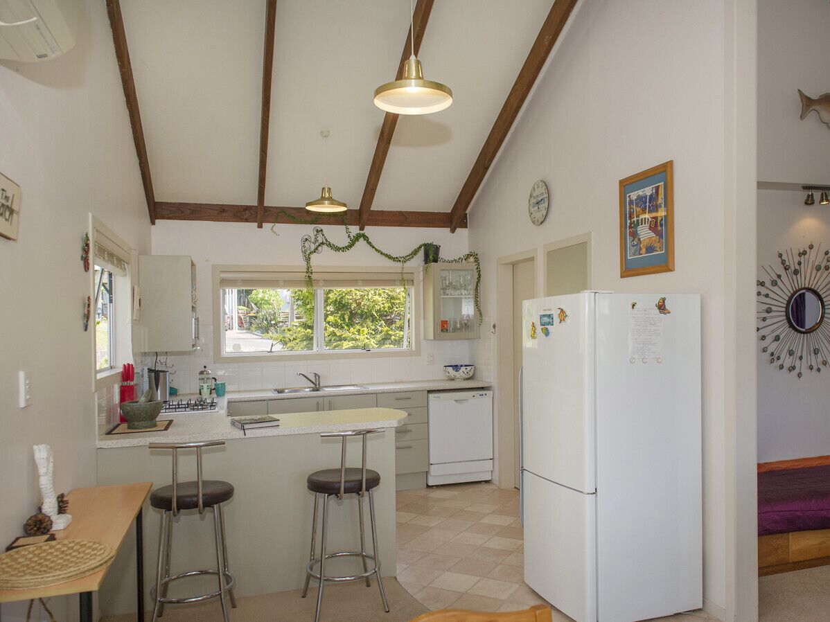 A compact kitchen with a central island, a refrigerator, and a dining area with stools.