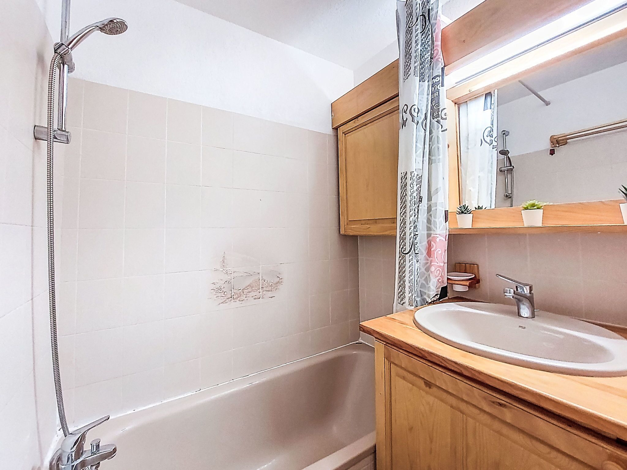 Een badkamer met een bad, wastafel, spiegel en douchekop.