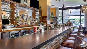 A bar area with a long counter, stools, and a variety of bottles and glasses. - Downtown Printer Row district Hotel style room (Chicago)