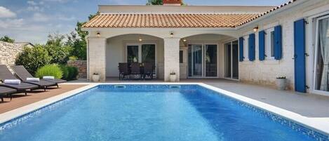 A swimming pool with lounge chairs and a patio area.