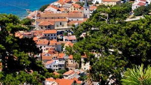 Une ville côtière avec des bâtiments aux toits de tuiles rouges, une plage et des bateaux sur l’eau.