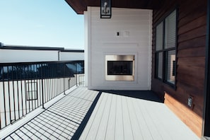 Un balcón con cubierta de madera, una chimenea y vistas al cielo.