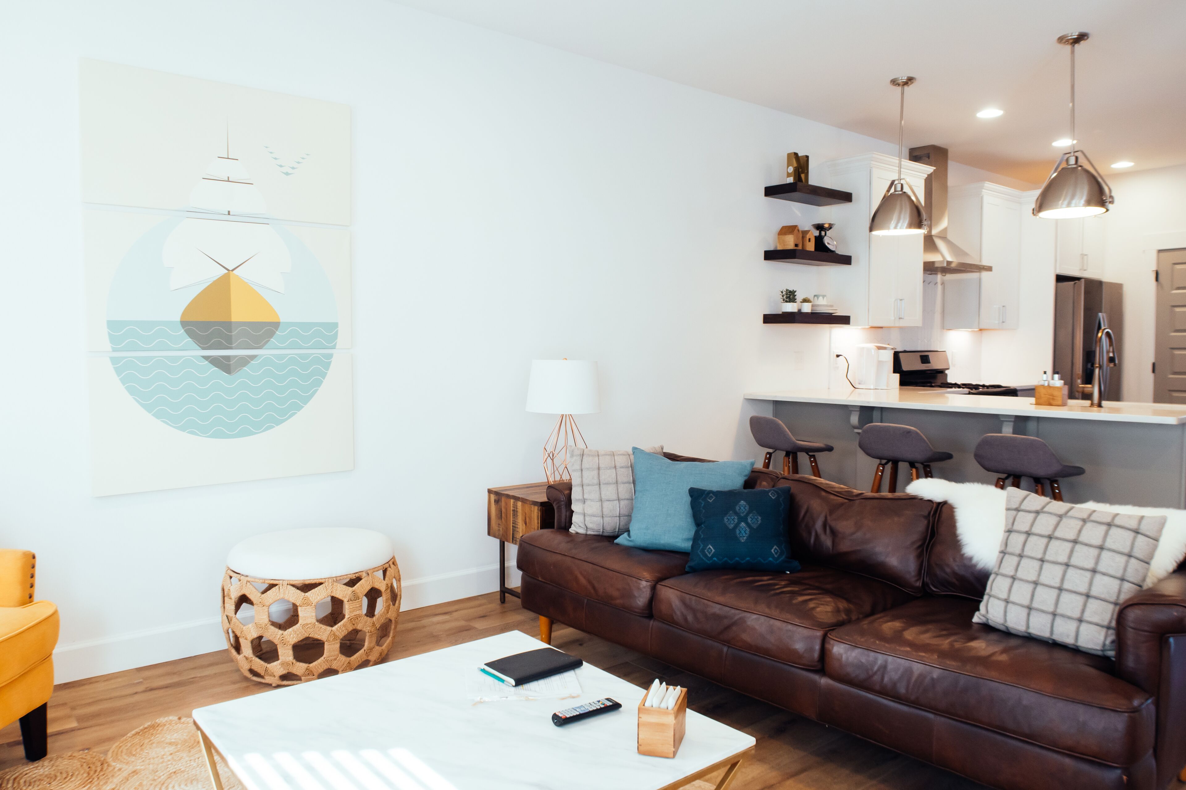 A modern living room with a brown leather sofa, a white coffee table, and a large abstract painting on the wall.