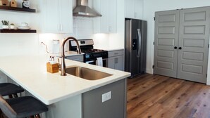 A modern kitchen with a central island, stainless steel appliances, and wooden flooring.