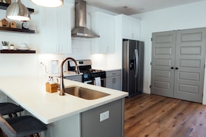 Una cocina moderna con una isla central, electrodomésticos de acero inoxidable y suelo de madera.