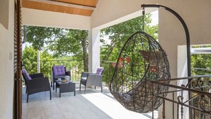Un espacio de estar al aire libre techado con mobiliario de mimbre y una silla colgante.