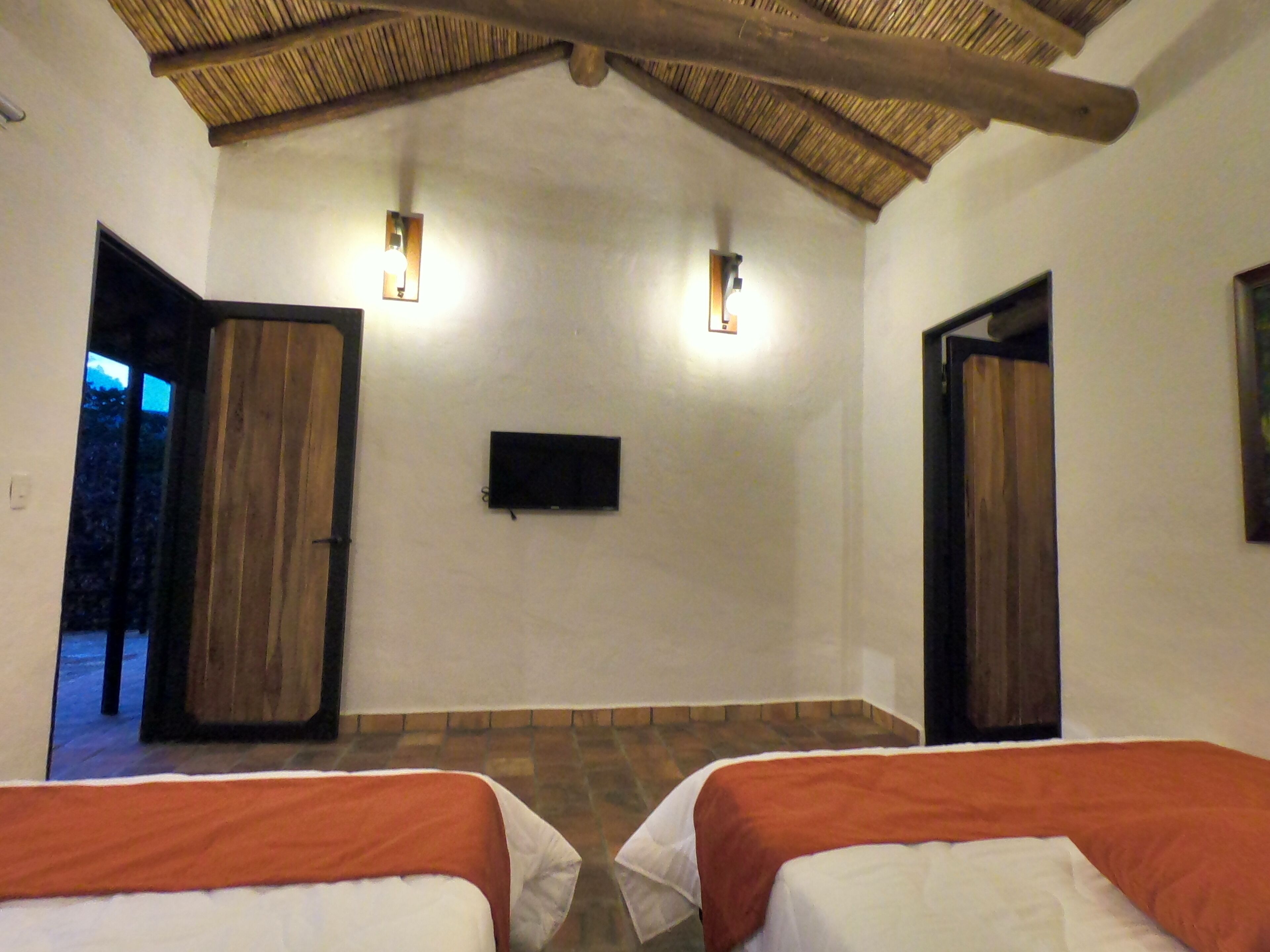 Een kamer met twee bedden, een televisie en een deur naar buiten.