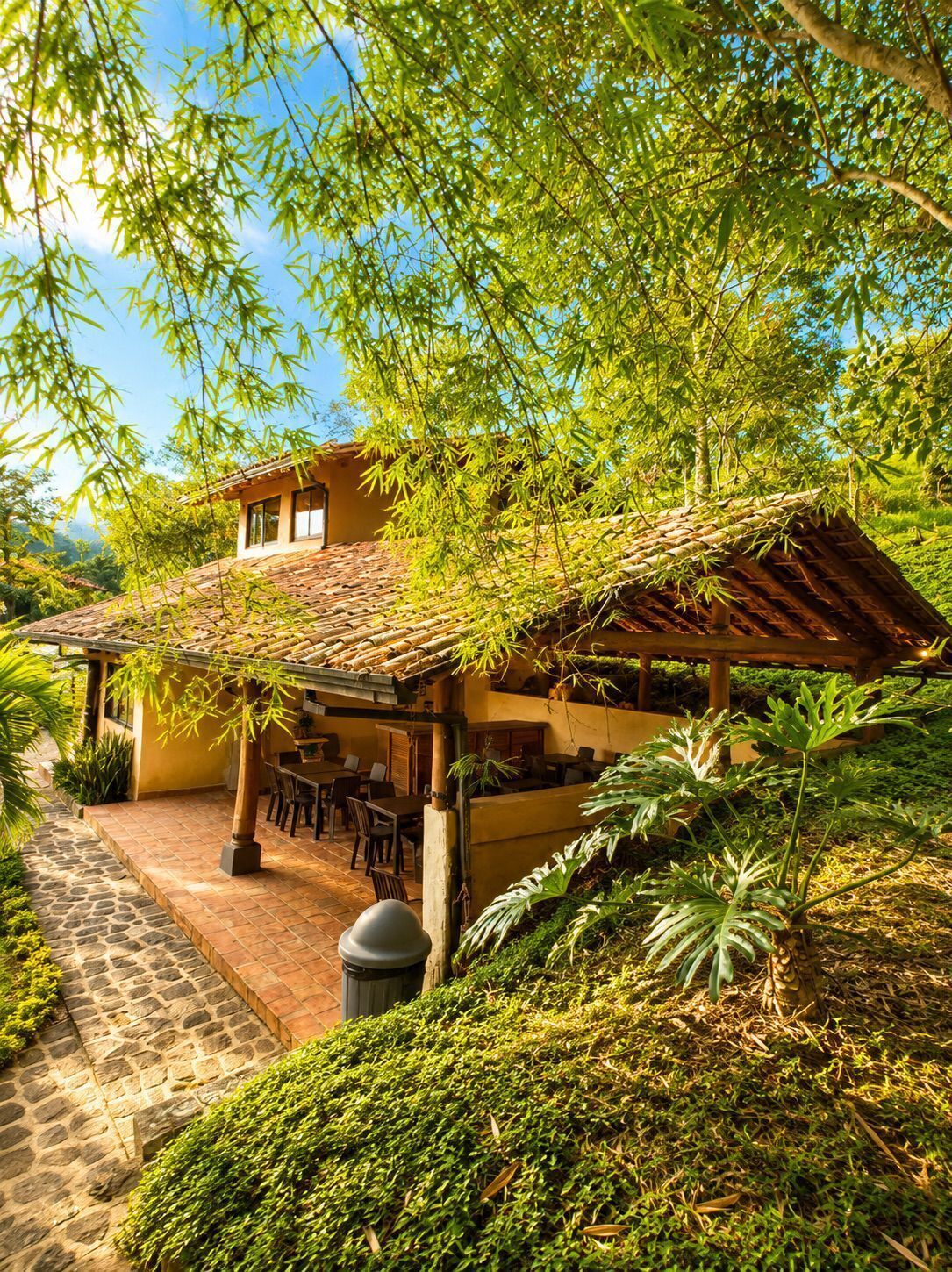 Un bâtiment doté d’un toit en tuiles, d’une terrasse et d’une végétation luxuriante.