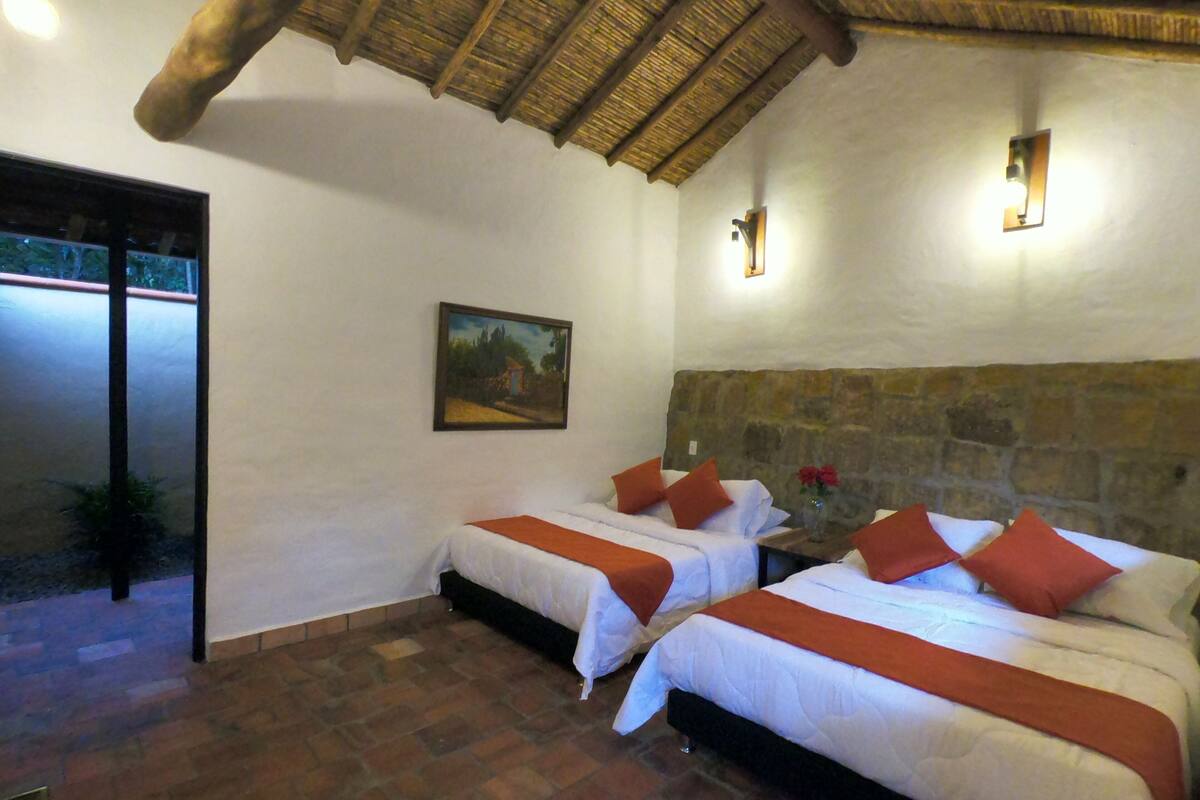 Ein Zimmer mit zwei Betten, einer Steinwand, einem Gemälde und einer Reetdeckung.