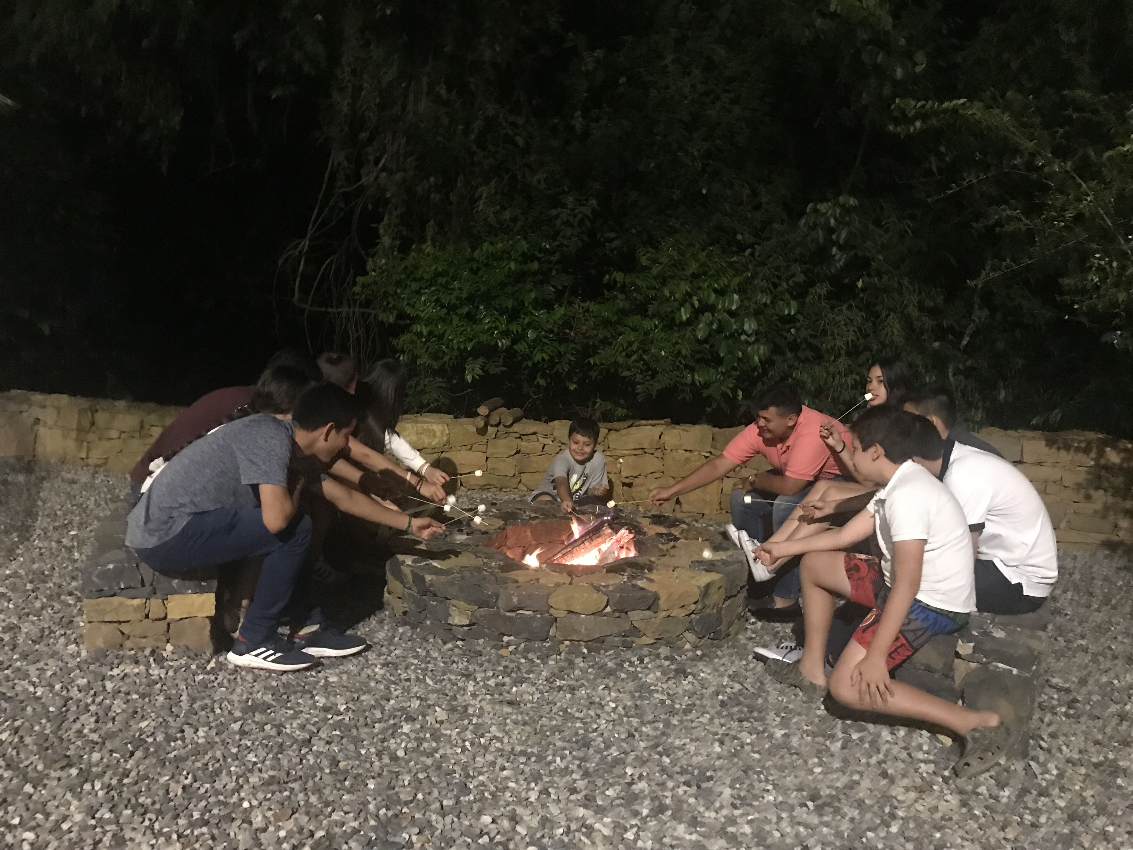 A group of people around a stone fire pit at night.