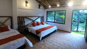 A room with two beds, a wooden ceiling, a large window, and a view of greenery outside. - Hotel casas de Campo El Ciruelo (San Gil)