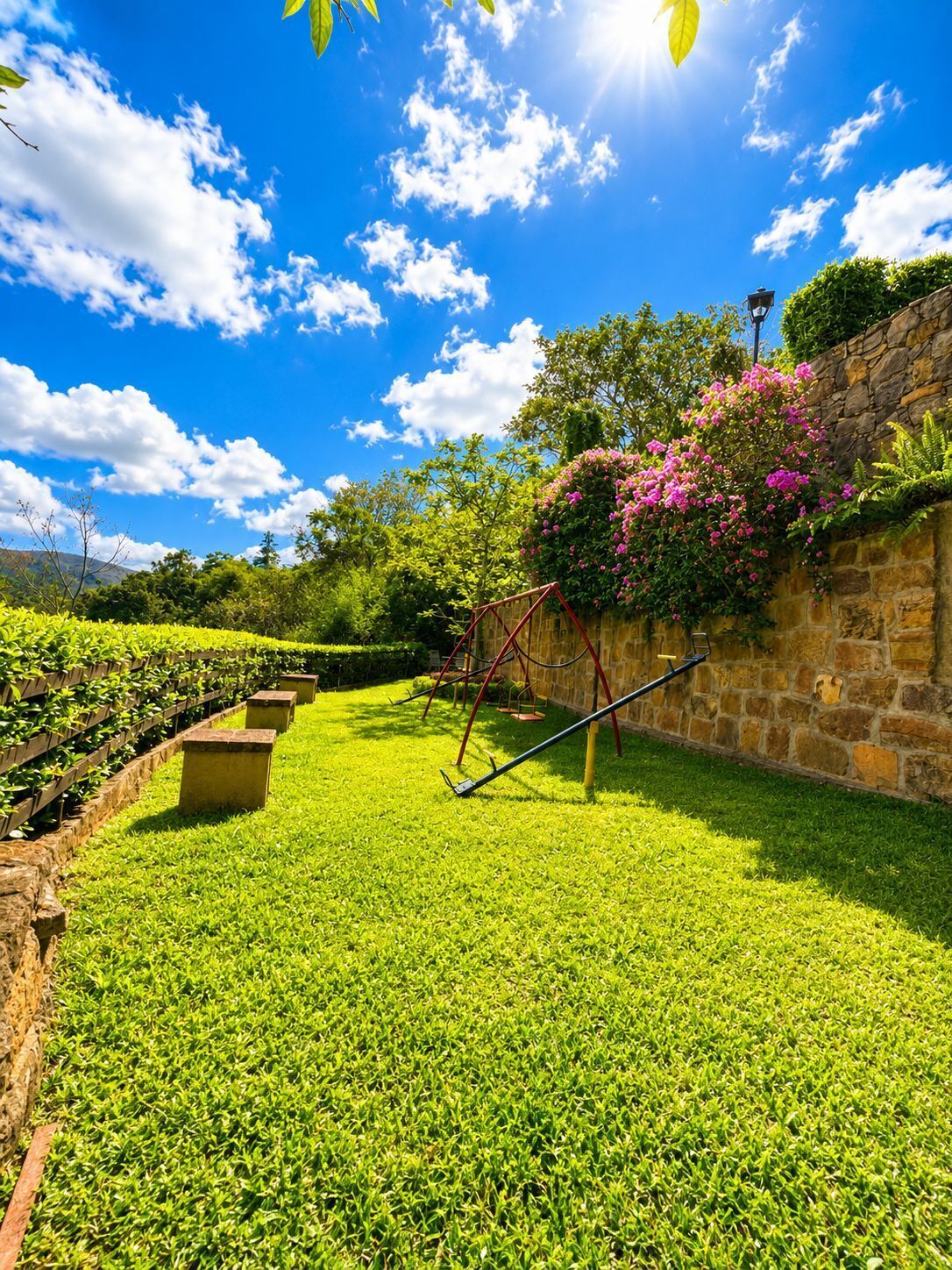 A well-maintained garden with a stone wall, flowering plants, and a metal swing set.