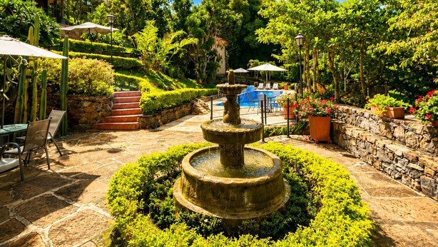 A garden with a fountain, stone steps, and outdoor seating. - Hotel casas de Campo El Ciruelo (San Gil)