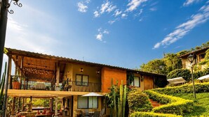 A spacious outdoor patio area with a stone floor, surrounded by lush greenery and cacti. - Hotel casas de Campo El Ciruelo (San Gil)