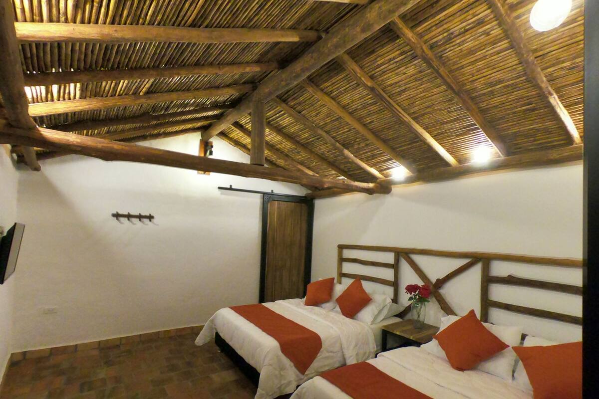 Ein Zimmer mit zwei Betten, Holzboden und Ziegelböden.
