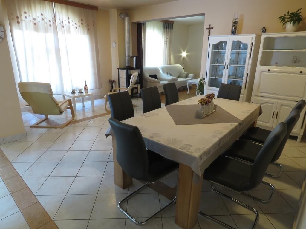 A dining area with a table and chairs, a sofa, and a cabinet in the background.
