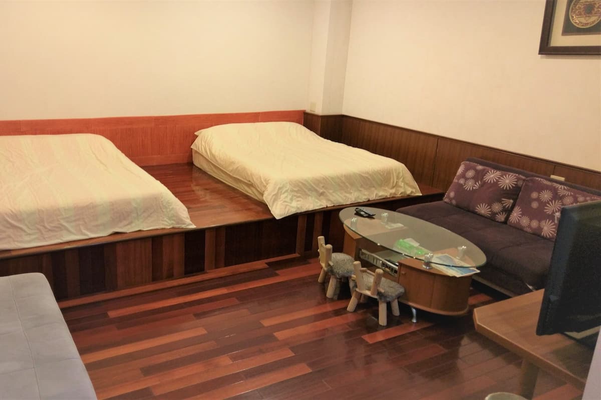 Une petite pièce avec deux lits, un canapé, une petite table et un téléviseur.