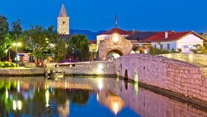 A historic stone bridge over a calm river, a church with a bell tower, and traditional buildings with red roofs. - Apartment in Nin with Seaview, Terrace, Air condition, WIFI (4868-3) (Nin)
