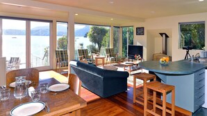 A spacious living area with a large sofa, dining table set, and a kitchen island. - Ngaire's Haven - Mahau Sound Holiday Home (Mahau Sound)