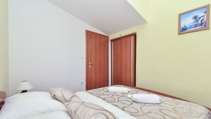 A hotel room with two beds, a nightstand, a lamp, and a painting on the wall.
