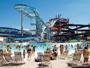 A water park with multiple water slides and a swimming pool area with lounge chairs and people.