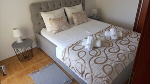 Una cama bien hecha con una colcha estampada, dos almohadas y una mesita de noche con una lámpara.