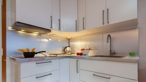 Una cocina moderna con armarios blancos, manijas de acero inoxidable y una sartén negra sobre la encimera.