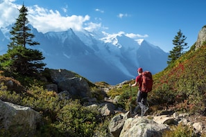 Un randonneur sur un sentier rocailleux, avec des montagnes en arrière-plan.
