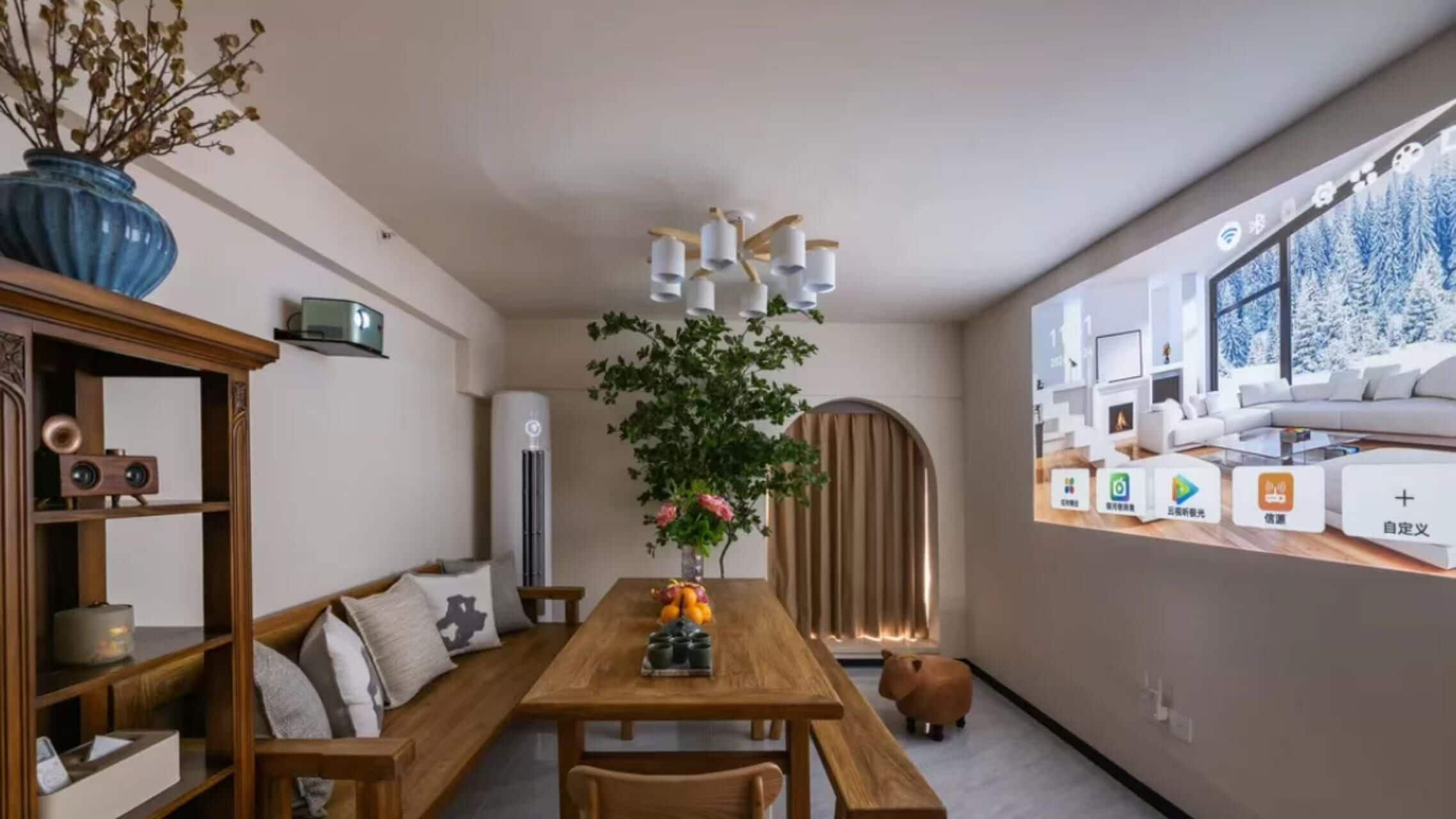 A modern dining area with a wooden table, chairs, and a vase with flowers. There is a large window with a view of a snowy landscape.