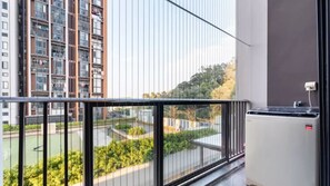 Un balcon donnant sur un quartier résidentiel, avec vue sur une rue et des espaces verts.