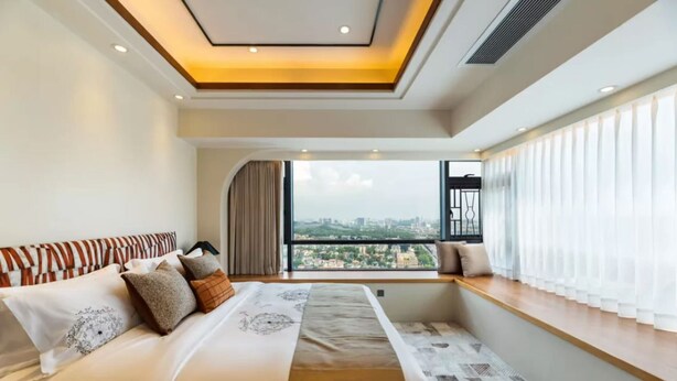 Ein modernes Hotelzimmer mit einem großen Bett, Blick auf die Stadt und einem Oberlicht.