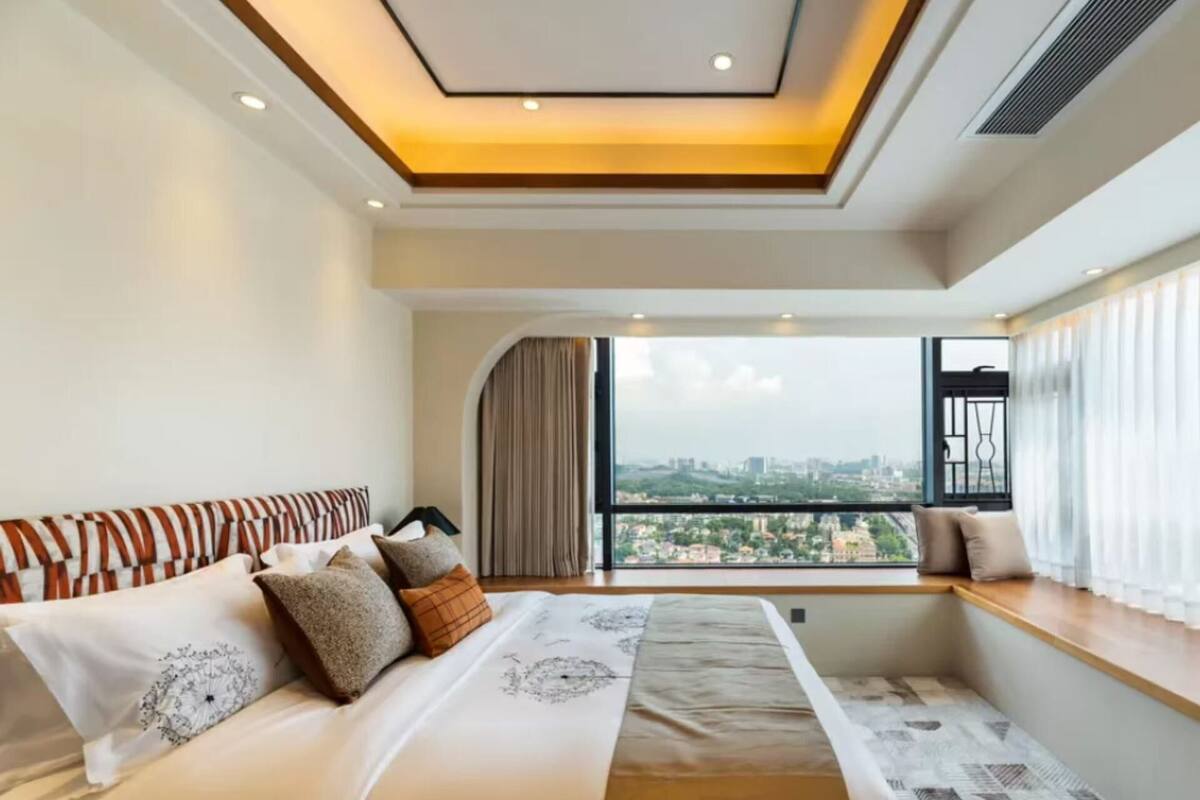 A modern hotel room with a large bed, a view of the city, and a skylight.