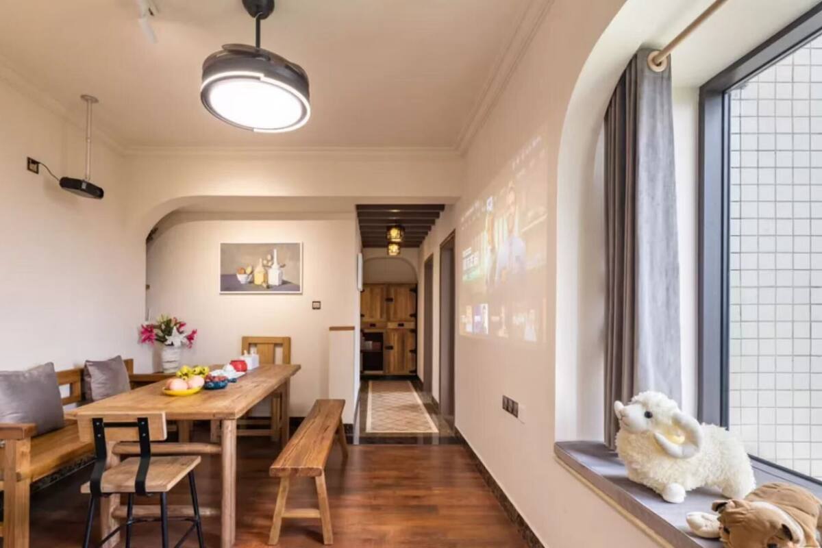 A dining area with a wooden table, benches, and a bench seat. There is a window with a view of the outside.