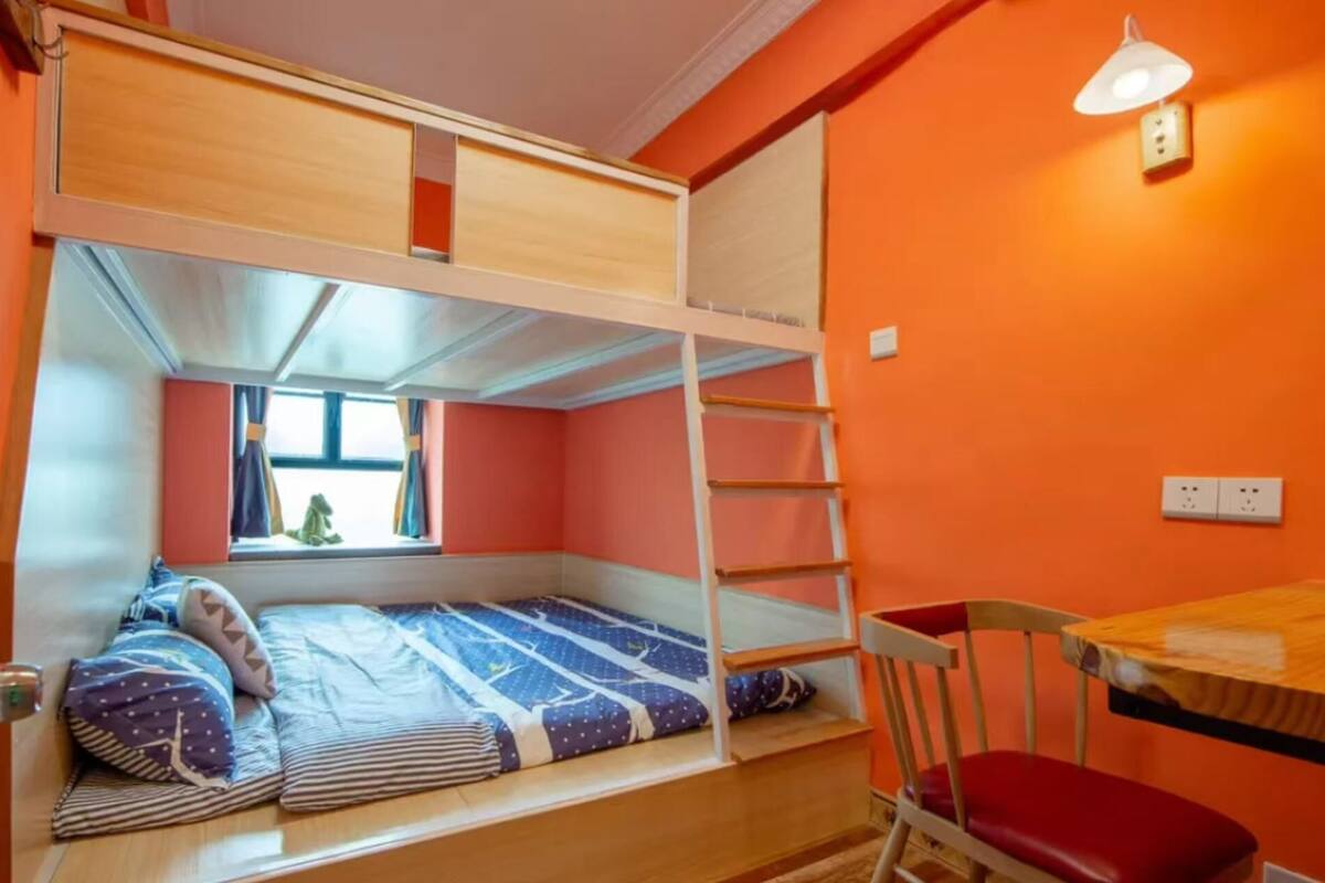 A bunk bed room with a window, a desk, and a chair.