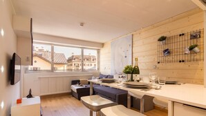 A modern kitchen with a dining area, wooden flooring, and a large window overlooking buildings. - Apt Le Concordia 4 Chic 2BR in Chamonix Centre | Ski, Chamonix, France (Chamonix)