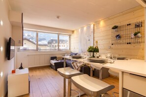 Une cuisine moderne avec un coin repas, une grande fenêtre et une vue sur les bâtiments environnants.