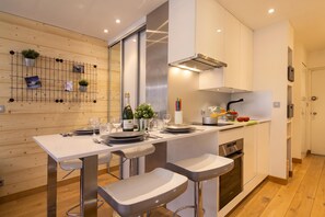 Una cucina moderna con isola centrale, sgabelli da bar e tavolo da pranzo per quattro persone.