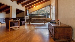 Un salón con suelo de madera, un sofá, una mesa de centro de madera y un banco.