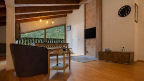 Una habitación con techo de madera, un sofá, una mesa con bandeja, un reloj en la pared y vistas a través de una ventana.